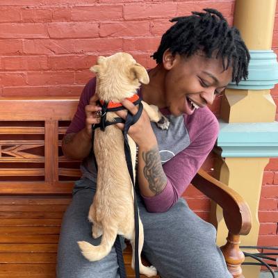 Elija with a small adoptable dog in his lap